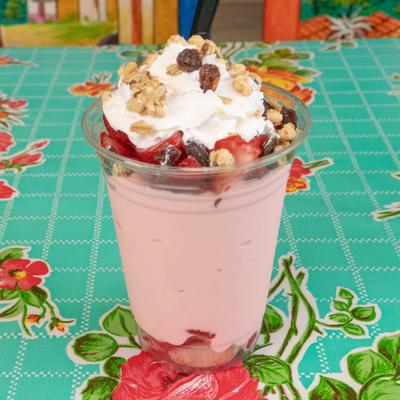 Strawberries and Cream served in a plastic cup, topped with whipped cream and granola.