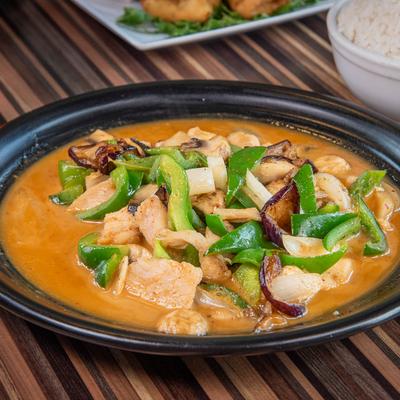 Thai chicken curry stir-fry with green peppers, onions, and creamy orange sauce served with rice.
