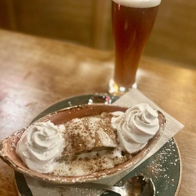 A dessert with whipped cream and cinnamon, served with a tall glass of beer.