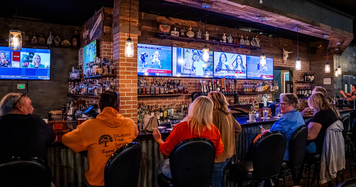 Bar, guests, tv's above drink rack