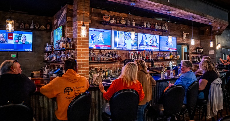 Bar, guests, tv's above drink rack