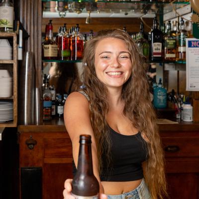 A bartender serves a bottle of beer on a bar counter.
