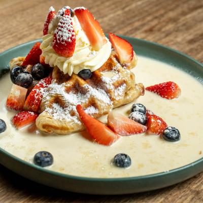 A crisp croffle topped with fresh berries, whipped cream, served in a sweet sauce.