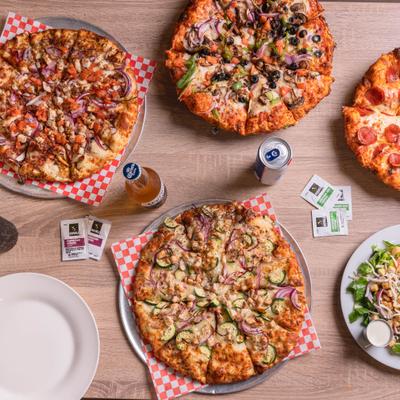 Assorted pizzas, salad, and drinks on a table.