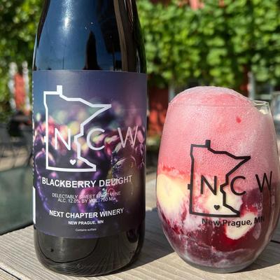 A bottle of Blackberry Delight Wine next to a glass of Blackberry Wine Float at Next Chapter Winery.