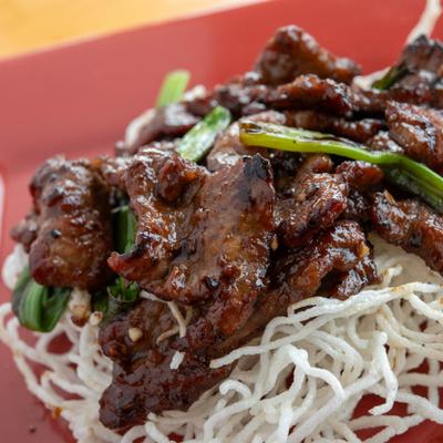 Mongolian Beef served over crispy fried rice noodles, close-up.