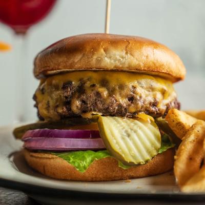 Brisket burger with cheddar cheese, pickles, and red onions, served with fries.
