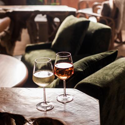 Two glasses of wine sit on a table in front of a cozy couch.