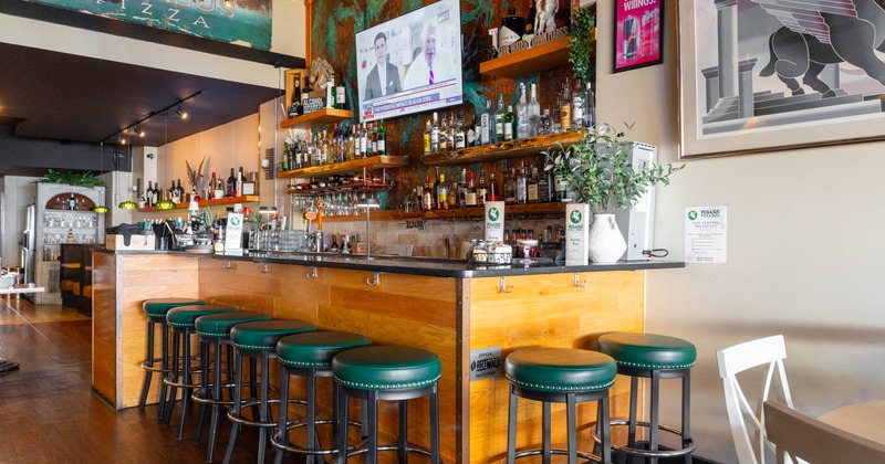 Interior, wooden front and marble top bar with padded stools, drink shelf and TV on the wall
