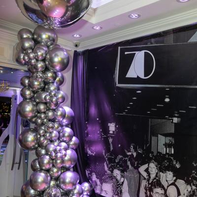 Silver balloon column beside black event backdrop.