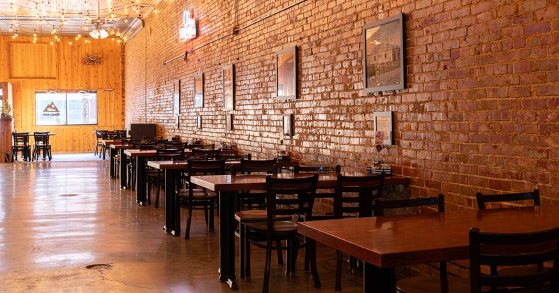 Interior, dining area, wooden top tables for four, vintage red brick wall, concrete flooring