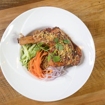 Grilled chicken with herbs and crushed nuts served with julienne vegetables on a plate.