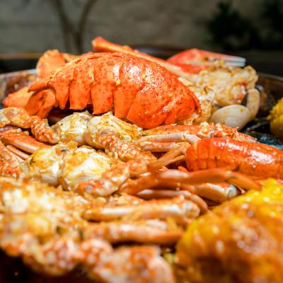Seafood boil with lobster tails, crabs, crawfish, corn, potatoes, and sausage, close-up.