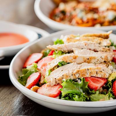 Grilled chicken and strawberry salad with mixed greens and crumbled cheese.