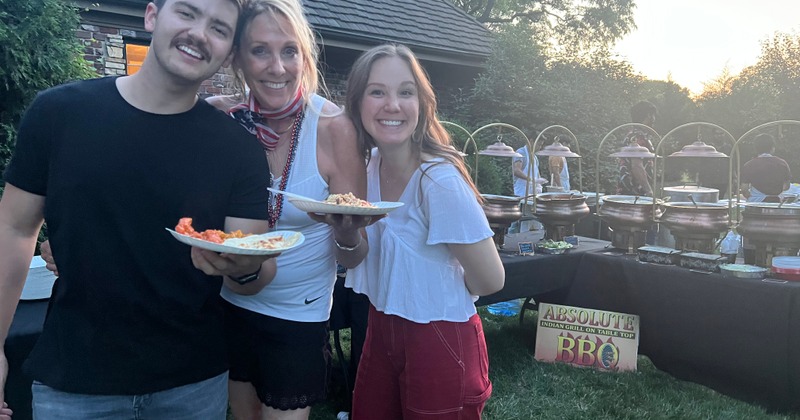 A group of smiling guests posing for the shot at an outdoor buffet event