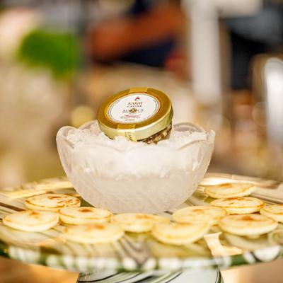 A jar of caviar on ice with blini pancakes around it.
