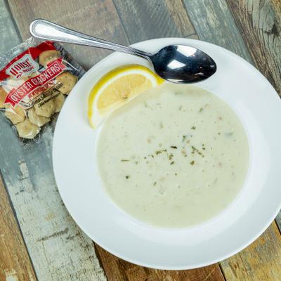 Clam chowder served with a lemon wedge and a packet of crackers.