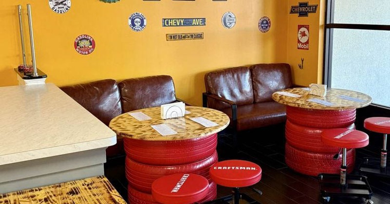 Automotive decorated interior with tables made from tires, stools and vintage memorabilia