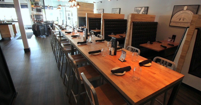 Interior, lined up tables for dining, with tableware, glasses and napkins