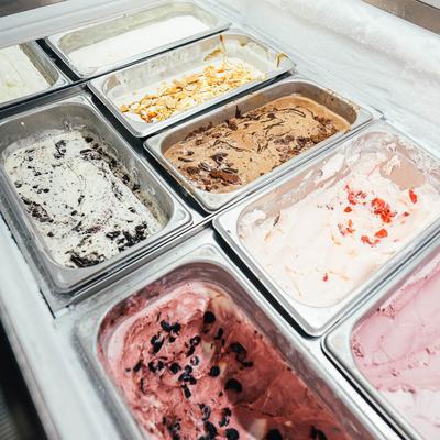 Ice cream display counter compartments with different ice cream flavors.