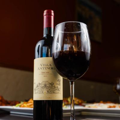 A bottle and a glass of red wine on a table.