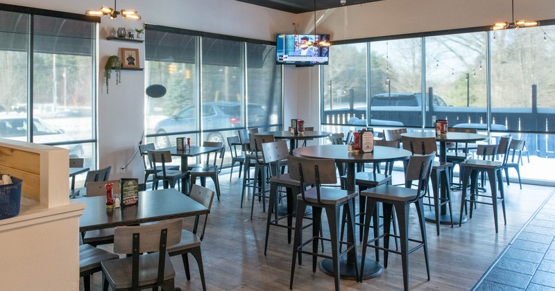 Interior, high and regular seating area, tables with chairs, large surface windows