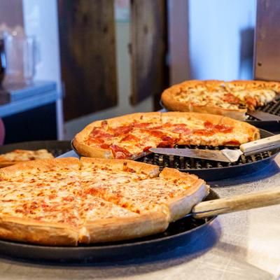 Three pizzas lined up on a counter.