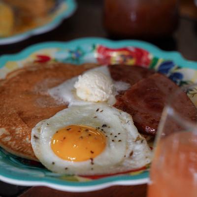 Pancakes served with a sunny-side-up egg, ham, and butter.