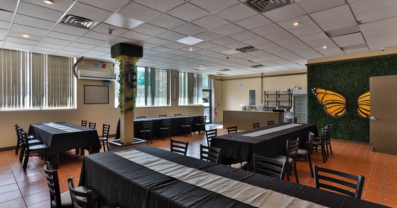 Dining area with black-clothed tables and a butterfly decoration on the wall