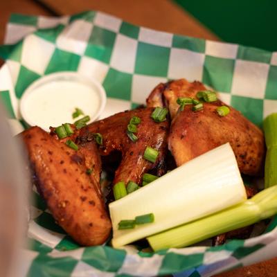 Dry Rub Wings garnished with scallions, served with celery sticks and a dip.