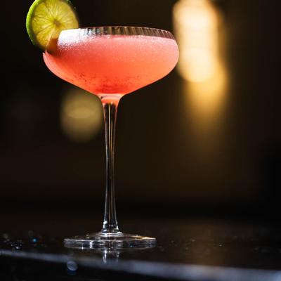 Strawberry Cosmopolitan cocktail in a coupe glass with a slice of lime.