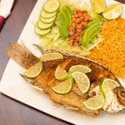 Whole fish garnished with lime and served with rice and salad.