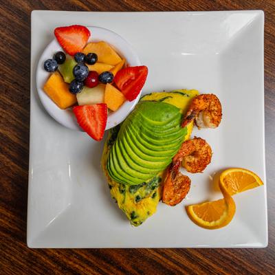 Avocado shrimp omelet with a side of fruit.