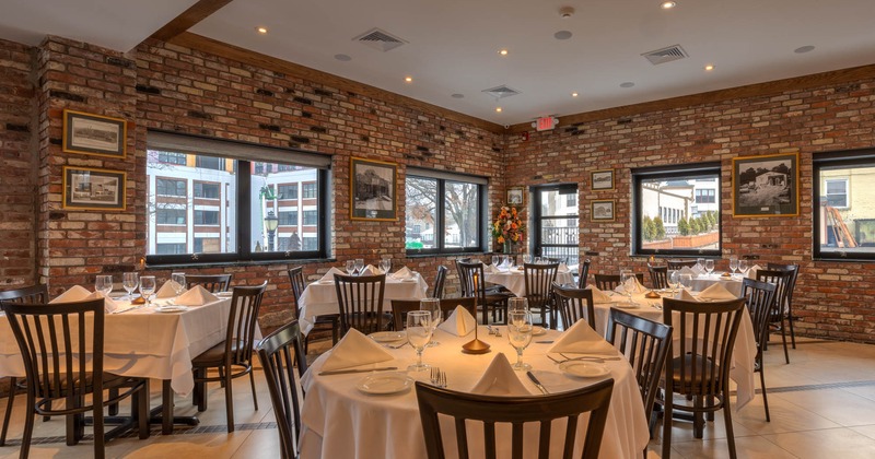 Interior, dining area, tables for four, ready for guests, vintage red brick walls, paintings