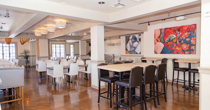 Spacious restaurant interior with tables, chairs, vibrant artwork