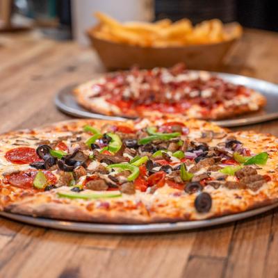 Sausage and pepperoni pizza topped with sliced green peppers and black olives.