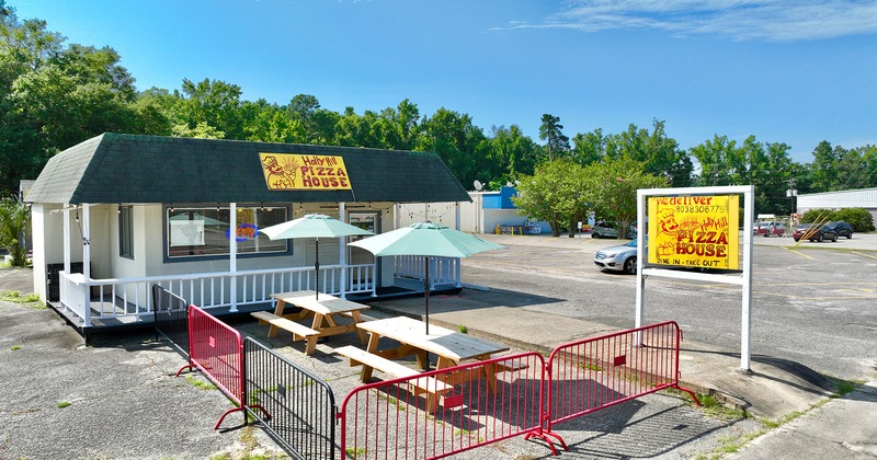 Pizza house exterior, outdoor seating area, conjoined tables and benches, and parasols