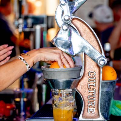 Person squeezing fresh orange juice using a manual press.