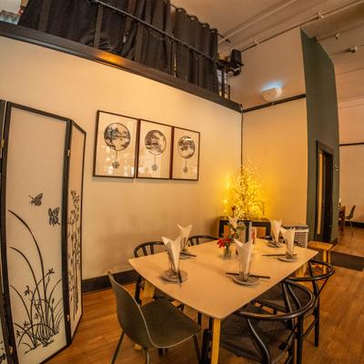 Warmly lit dining area with a set table and Asian-style wall art.