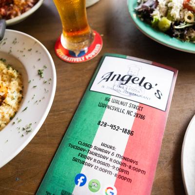 Restaurant menu displayed on the table beside a glass of beer and various dishes.