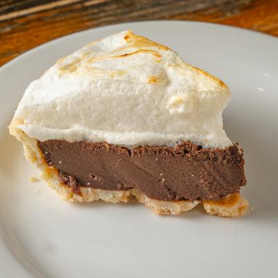A piece of chocolate meringue pie served on a white plate.