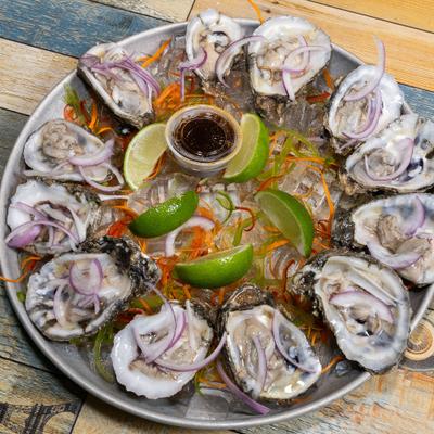 Oyster platter with lime wedges, onions, and dipping sauce.