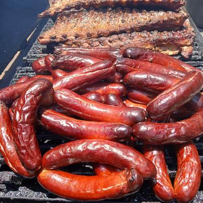 BBQ setup featuring grilled sausages and racks of pork ribs.