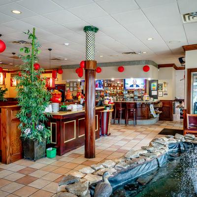 Restaurant interior with a bar, red lanterns, bamboo decor, and an indoor pond.