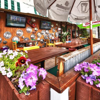 Outdoor patio with wooden tables, colorful chairs, and wall art made from hubcaps