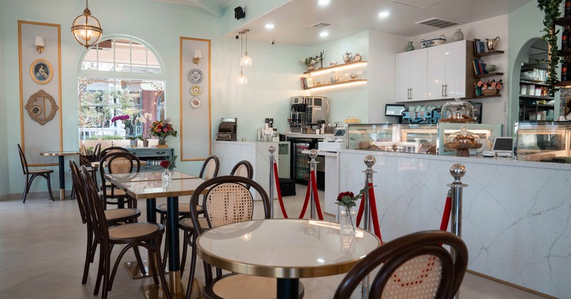 Elegant interior - mint green walls, tables, chairs and a display counter with pastries.