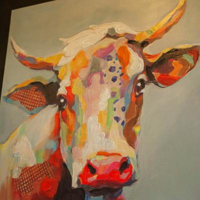 Wall art featuring a vibrant, multicolored depiction of a cow's head on a canvas.