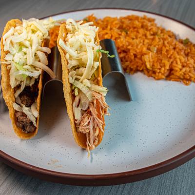 Ground beef taco and crunchy chicken taco served on a plate with rice.