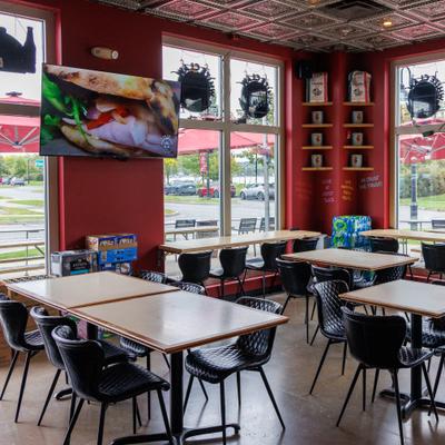 Interior with red walls, large windows, wooden tables, and black chairs.