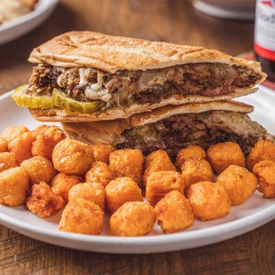 Pulled pork sandwich with cheese and pickles, served with tater tots